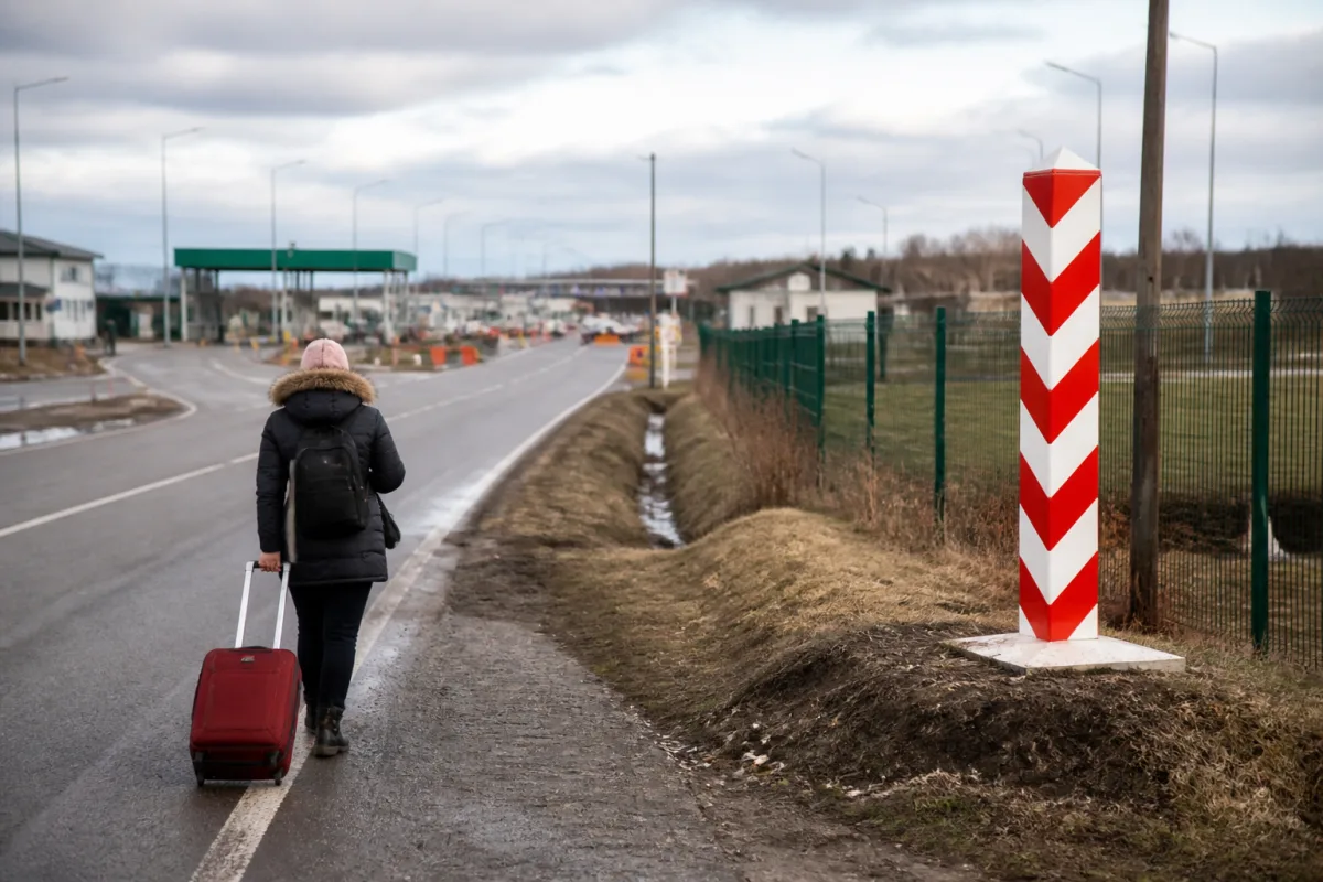 Человек пересекает границу Украины и Польши с чемоданом — символ потери доплаты при выезде