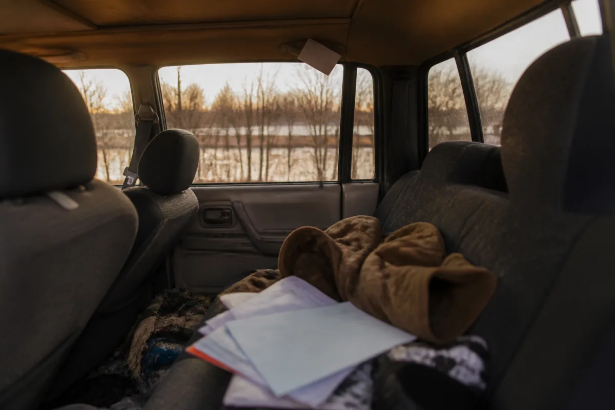 A person with personal belongings living in a car during a period of homelessness after a relationship crisis